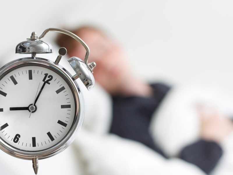 hombre durmiendo con su alarma a punto de sonar