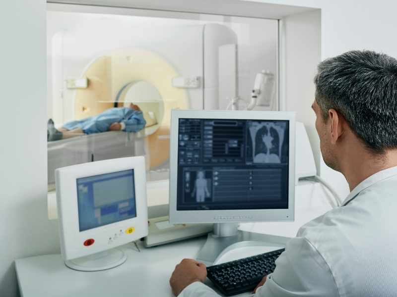 Radiólogo revisando imágenes de tomografía computarizada en un monitor.
